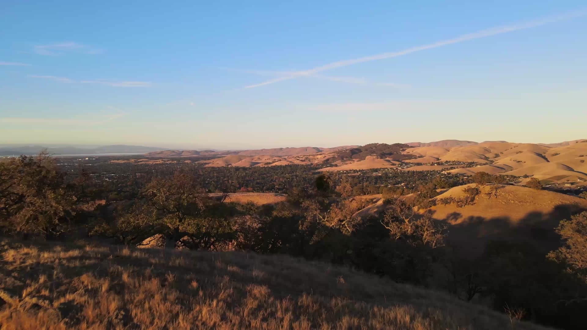 Aerial view of golden South County foothills and a valley neighborhood at sunset, illustrative